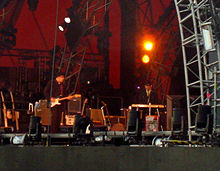 Dylan, standing and playing the keyboards, onstage with members of his band.