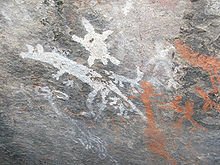 muro de piedra gris con dibujos primitivos blanco y naranja