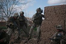 Soldados ao lado de um muro de barro