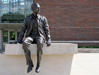 Photo of a statue of Neil Armstrong sitting on a ledge. As palavras